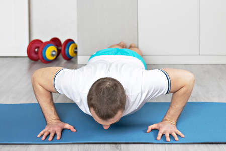 A strong, healthy man with muscles, training at home in the plank position. fitness at homeの写真素材