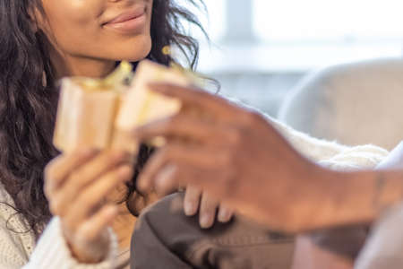 A happy couple of mulattoes exchange gifts with each other. Celebrating joint family eventsの写真素材
