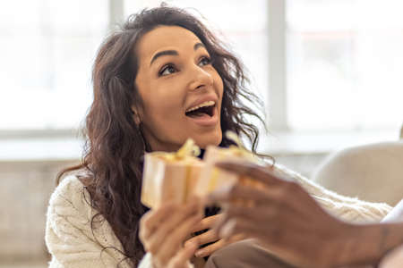 A happy couple of mulattoes exchange gifts with each other. Celebrating joint family eventsの写真素材