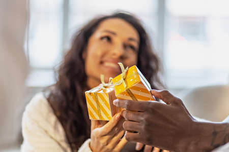 A happy couple of mulattoes exchange gifts with each other. Celebrating joint family eventsの写真素材