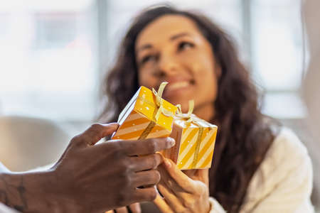 A happy couple of mulattoes exchange gifts with each other. Celebrating joint family eventsの写真素材