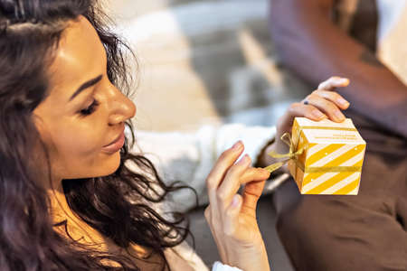 A happy couple of mulattoes exchange gifts with each other. Celebrating joint family eventsの写真素材