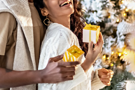 A happy couple of mulattoes exchange gifts with each other. Celebrating joint family eventsの写真素材