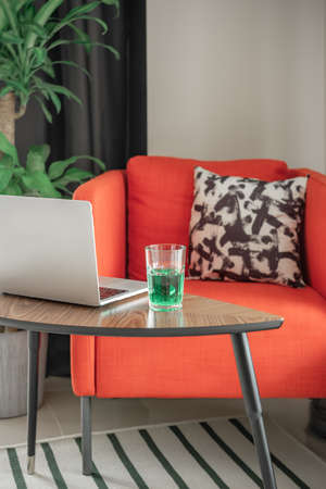 Cozy armchair, laptop and a glass of drink. vertical shot.の写真素材