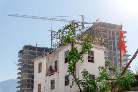 An old Turkish house against the backdrop of modern tall residential buildings under construction.