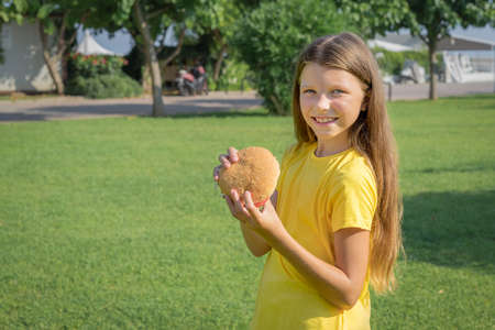 Happy teenage girl eating a burger in the park outdoors.の写真素材