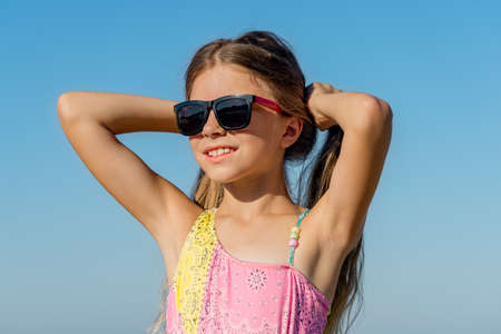 Cheerful girl in a swimsuit holds her hair with her hands at the resort.の写真素材