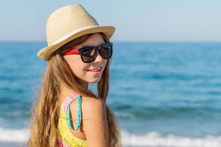 Portrait of a pretty smiling teenage girl on the background of the sea. Summer holidays at the seaside resort.の写真素材