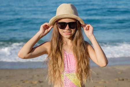 A teenage girl holds a hat with her hands on the background of the sea coast in Turkey.の写真素材