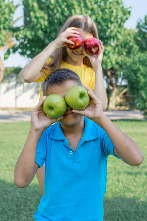 Cheerful teenagers children play with apples outdoors. vertical shot.の写真素材
