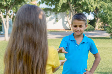 The girl holds out an apple to the boy. Useful snack.の写真素材
