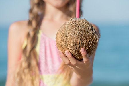 A hand with a coconut in hand and a pink straw for drinking. selective focus.の写真素材