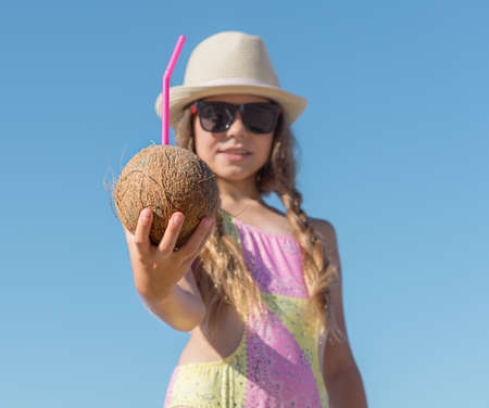 Girl Stretches out her hand with a coconut and a straw against the sky. selective focus.の写真素材