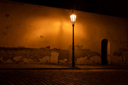 light from a lit street light in a city street at night. glowing lamp at night in the old town of...
