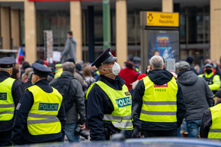 police officers supervise a crowd of people during a demonstration against government measures in the center of prague on the namesti republic in the czech republic in the rain on october 28のeditorial素材