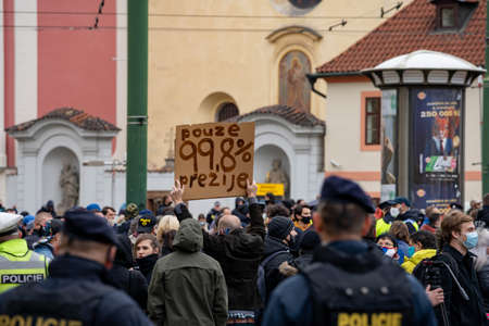 Police officers oversee a crowd of people demonstrating against government measures in the center of Prague on the Republic Square in the Czech Republic in the rain on October 28のeditorial素材