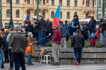 Police officers oversee a crowd of people demonstrating against government measures in the center of Prague on the Republic Square in the Czech Republic in the rain on October 28のeditorial素材