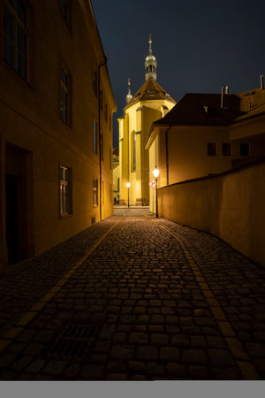 street lights on an illuminated street and pebbles on the ground in the center of the old town of prague at night in the czech republicの写真素材
