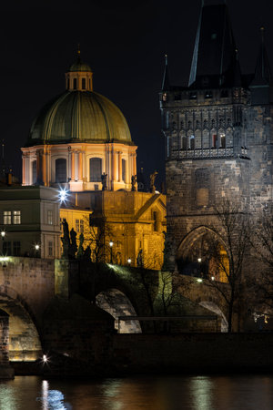old illuminated stone Charles Bridge and lights from street lights are reflected on the surface of the Vltava River in the center of Prague at night in the Czech Republicの写真素材