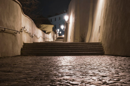 light from street lights and sidewalk and cobblestones on the ground at night in the center of Pragueの写真素材