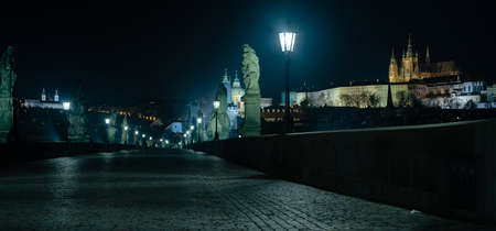 Rows of lamps on the empty Charles Bridge on the Vltava river at night and the stone bridge tower in the center of Pragueのeditorial素材