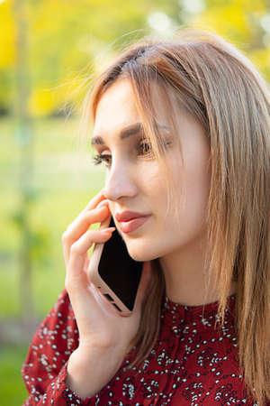Front view of business happy young woman walking and using smartphone on city street
