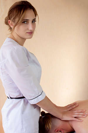 Masseuse applying pressure to the neck area.Collar zone massage - strong male hands of a masseur. Neck and collar zone massageの写真素材