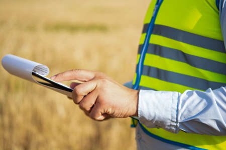 Close-up of an engineer's hands holding a folder in a wheat field in summer, a close-up of an...