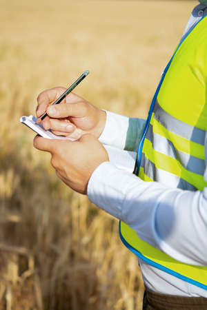 Close-up of an engineer's hands holding a folder in a wheat field in summer, a close-up of an...