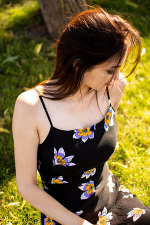 Cheerful young beautiful woman lying outdoors on green grass in city park.