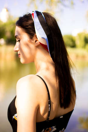 Cheerful young beautiful woman lying outdoors on green grass in city park.