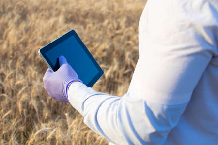 engineer in a helmet, glasses and a yellow vest, hand on a helmet, holding a notebook, a folder, making notes in a notebook a caucasian white engineerの写真素材