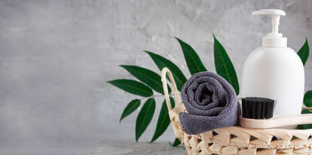 Gray towel, body massage brush, black bristle brush, foot penza, green ailanthus branch on gray background, bath accessories concept, bath productsの写真素材