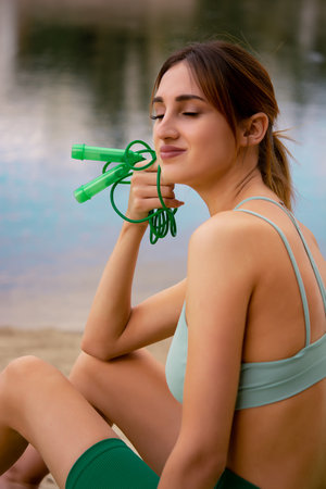 a young girl in a sports uniform is engaged in fitness, dressed in a green tracksuit top and bike shorts, water balance, outdoor sports, sports lifestyle, outdoor fitnessの写真素材