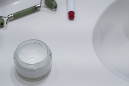 Face cream, face roller and lipstick near the sink on the counter in the bathroom, space for textの写真素材