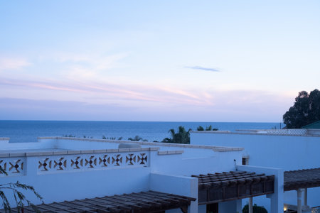 Palm trees against white home by the beach with blue sky and sand The top of the house or apartment with nice windowの写真素材