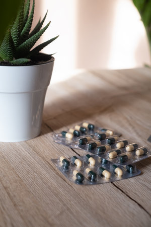Flat lay composition with a bunch of different colorful pills scattered on the table from a plastic...