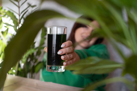 A woman holds a glass of chlorophyll water, an antioxidant drink. Healthy lifestyle, detox,...