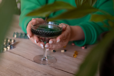A woman holds a glass of chlorophyll water, an antioxidant drink. Healthy lifestyle, detox, chlorophyll, proper nutrition, oxygenationの写真素材