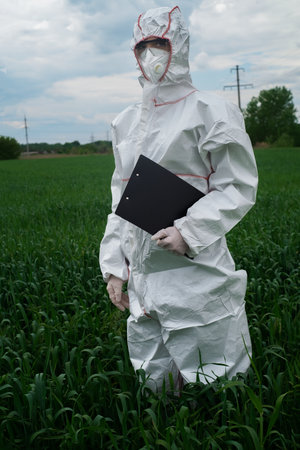 scientist in protective white PPE suit, treats seedlings, sprays leaves with fertilizers and fights...