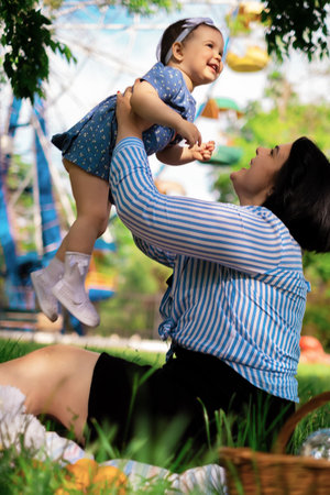 Beautiful mother and her cute daughter eat strawberries and tangerines in the park and enjoy a picnic day, family weekend, park vacationの写真素材