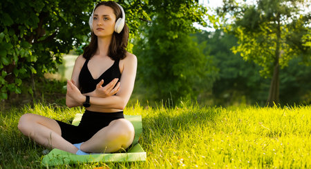 a young girl does yoga in a sports uniform, shows elements of sports and asanas. Green park in summer, concept of sport and healthy lifestyle.の写真素材