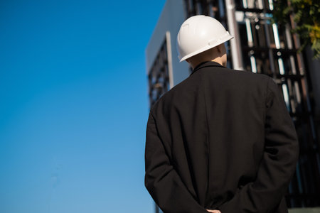 male foreman at a construction site looks at the quality of work, Architectural design holds a...