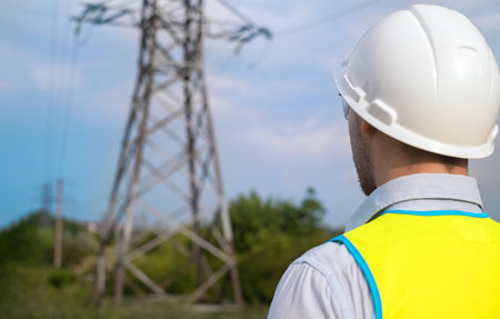 male engineer, power engineer in a helmet checks a power line using a tablet online. Electrician...