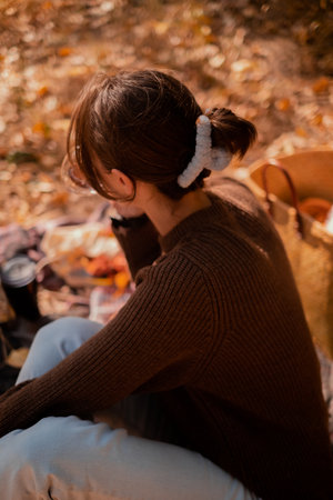 Autumn picnic outdoors, perfect autumn warm day, autumn picnic in nature, girl sitting on a blanket with a basket of groceries and a cup of hot tea, enjoying a sunny day, enjoying nature, solitudeの写真素材