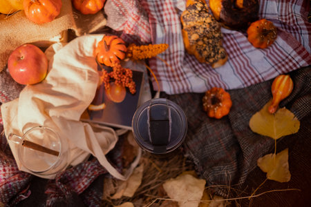 Thermos with cups of coffee and croissants on plaid in autumn parkの写真素材
