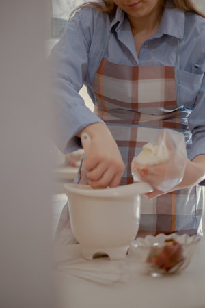 A female pastry chef prepares frosting for cupcakes. Enjoy the art of home baking with this homemade...