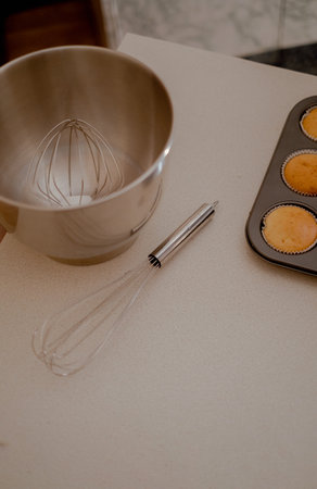 On the table are cupcakes, showcasing the artistry of a pastry baker. The kitchen table displays the...