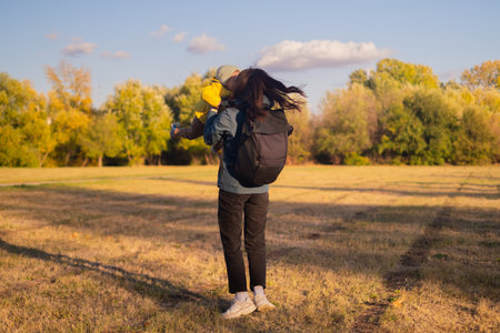 A woman with a backpack travels with her son, enjoying a family hike in the forest. They embrace an...