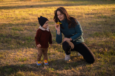 A mother and son play with paper airplanes in the park, enjoying family time outdoors. Celebrating Mother's Day with a fun-filled family day.の写真素材